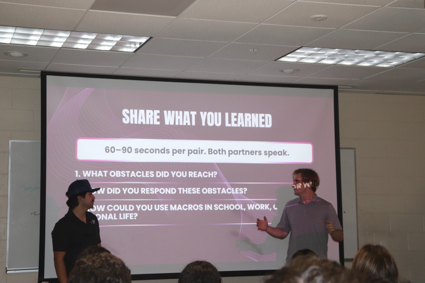 Christian presenting a slide titled Share What You Learned during an Excel macros workshop
